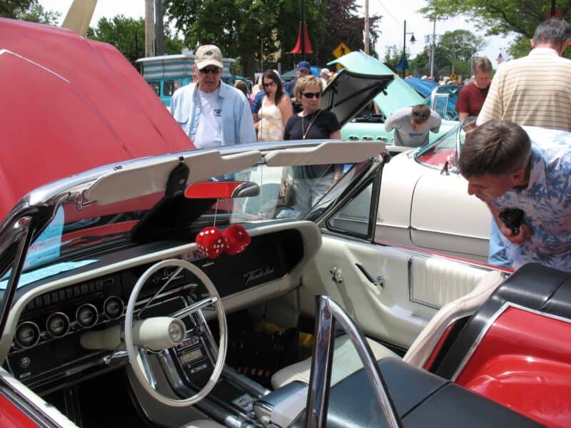 a man looking inside a red corvette convertible