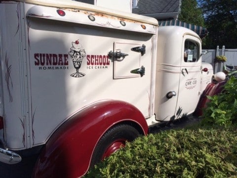 the red and white old fashioned Sundae School ice cream truck on the grass