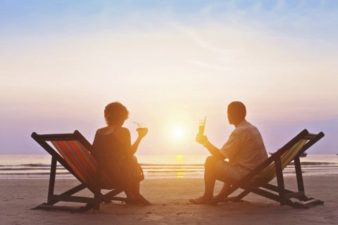 A couple on the beach at sunset sitting in beach chairs