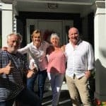 Four adults standing on a porch smiling