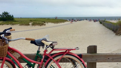 A bike parked near the sandy entrance to a beach