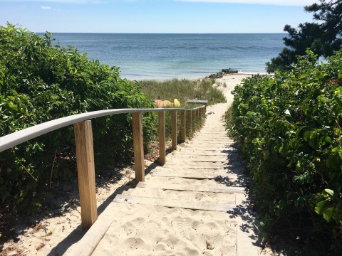 A staircase covered in sand leading down to the beach and ocean