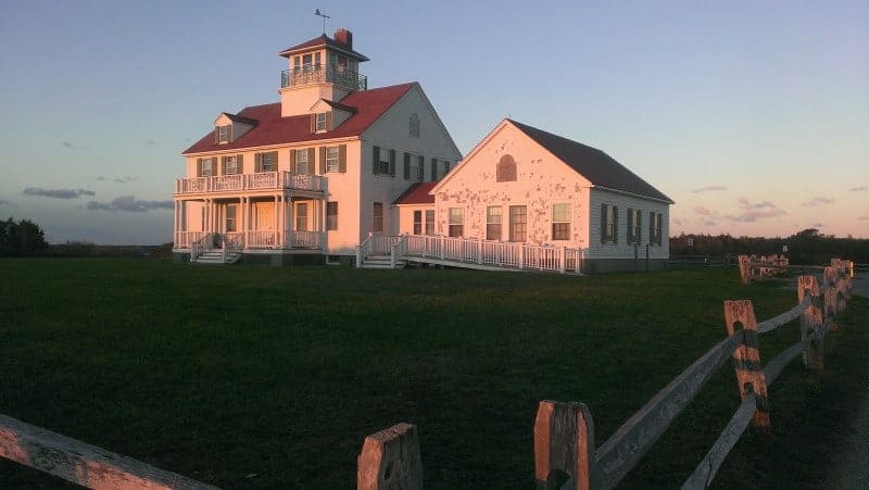 A white building at sunset with a wooden fence