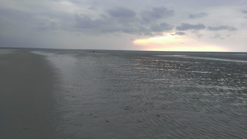 a totally calm beach and ocean at sunset