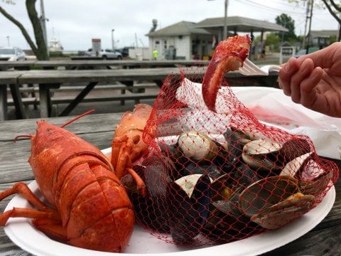 A lobster boil...a plate with a boiled lobster and a red bag filled with muscles and clams