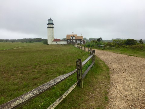 Cape Cod Lighthouse. White lighthouse with a brown building attached.  A dirt path with a fence leads up to the lighthouse