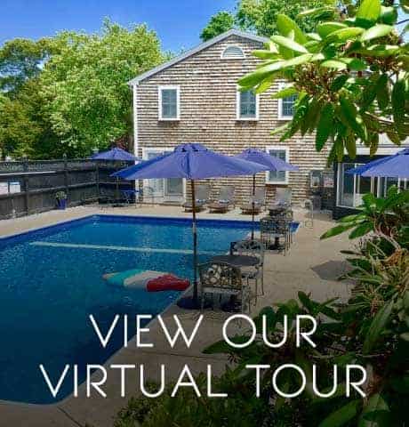 A clear blue pool with tables and umbrellas by the shingled building