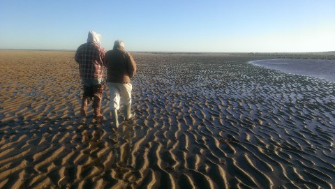 a couple walking along the beach at low tide
