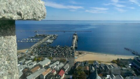 view from the top of the Pilgrim Monument looking towards the docks and the ocean with many houses looking small below