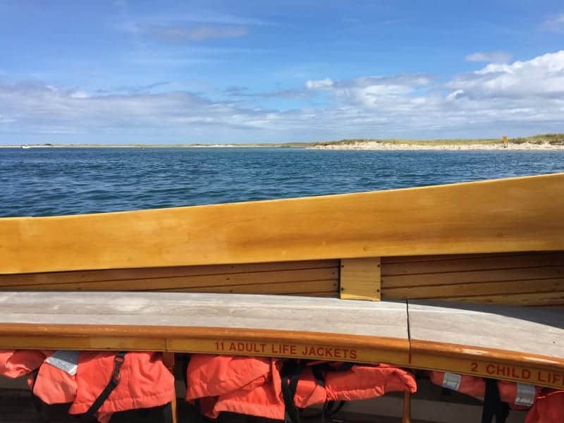 view from inside a boat with orange life vests on the floor, looking towards the ocean