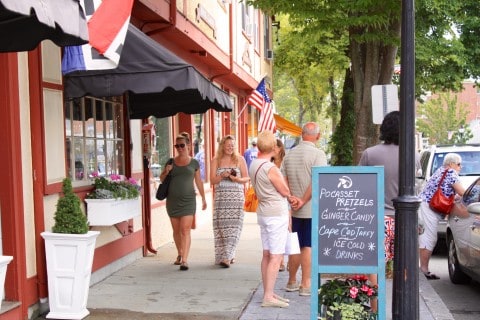 People walking along a sidewalk past restaurants and stores