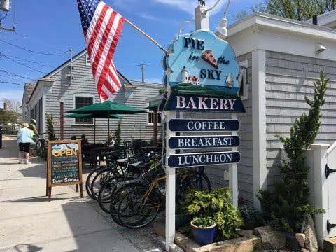 The outside of "Pie in the Sky" bakery in Falmouth.  An american flag is flying.  Several bicycles are parked outside.