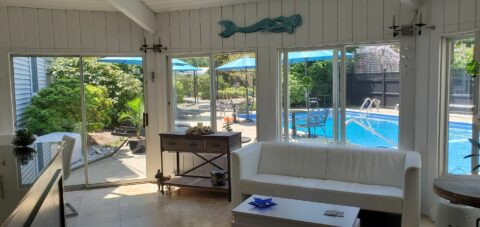 casual room with a white soft with windows opening to the view of a pool