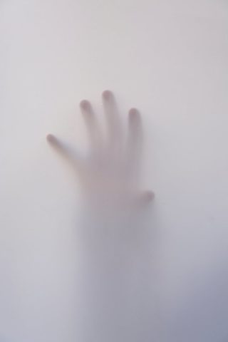 photo of a hand seen through foggy glass