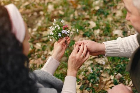 an old man giving flowers to an old woman