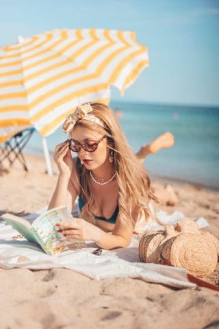 a woman reading a book on the beach