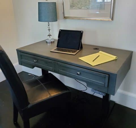 a photo of a chair and a desk with a laptop, table lamp, and notepad