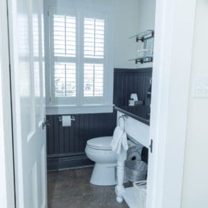 door open to a bathroom showing a shuttered window and toilet
