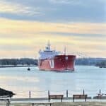 Red and white Barge on the Cape Cod canal with the Bourne Bridge in the distance