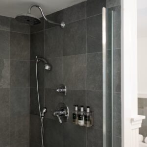 A grey tiled shower with glass door