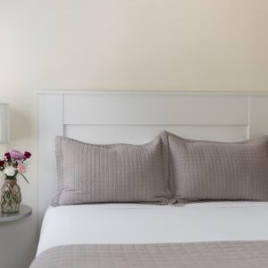 White bedroom with taupe accents. Silver bed side table with lamp and vase of flowers