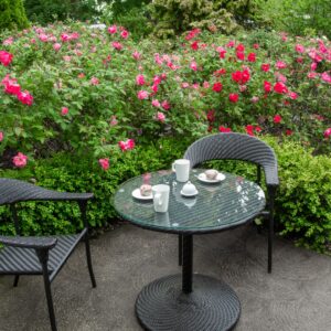 a table and chairs on a patio beside a rose garden
